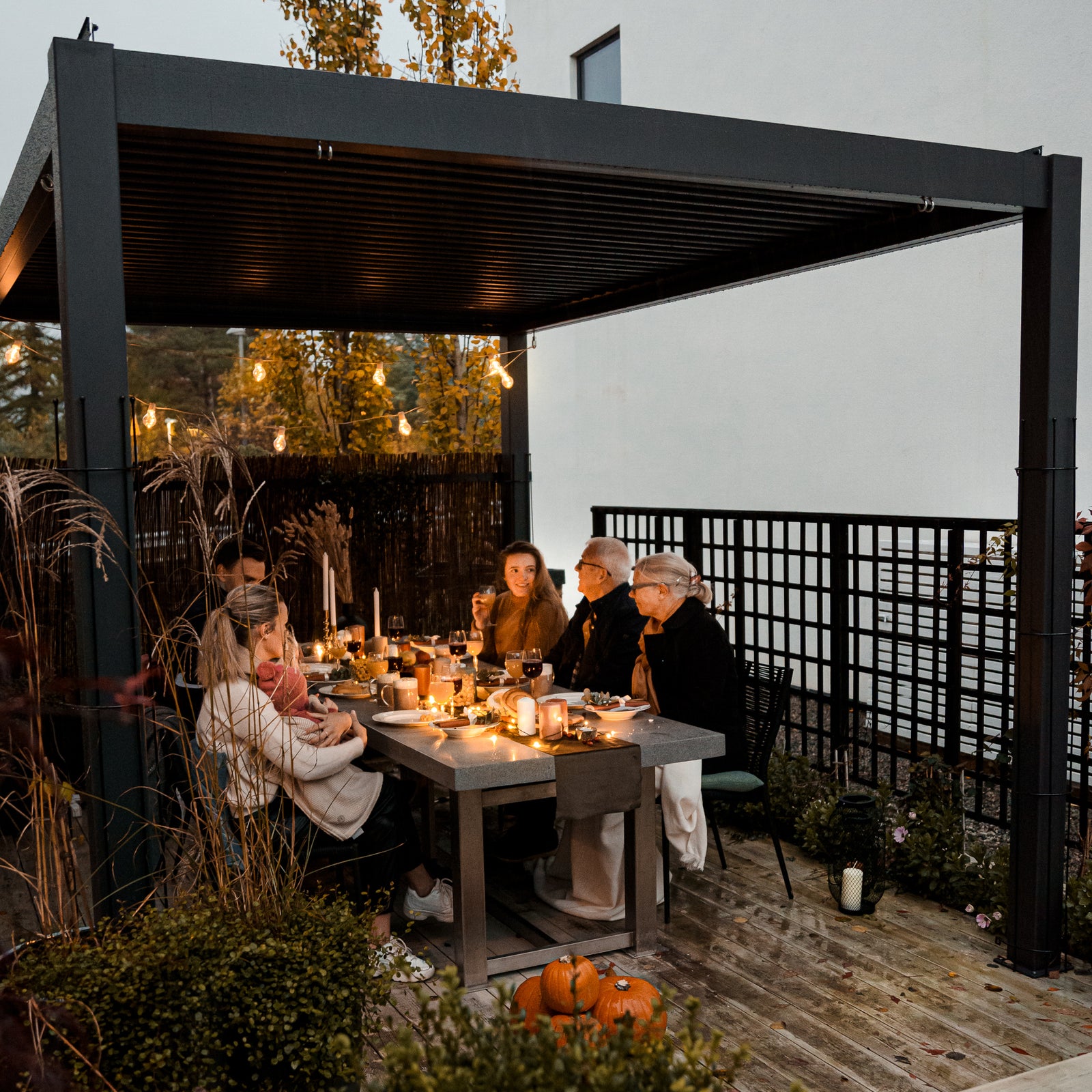 Anthricite pergola with louvered roof and dinner company beneath