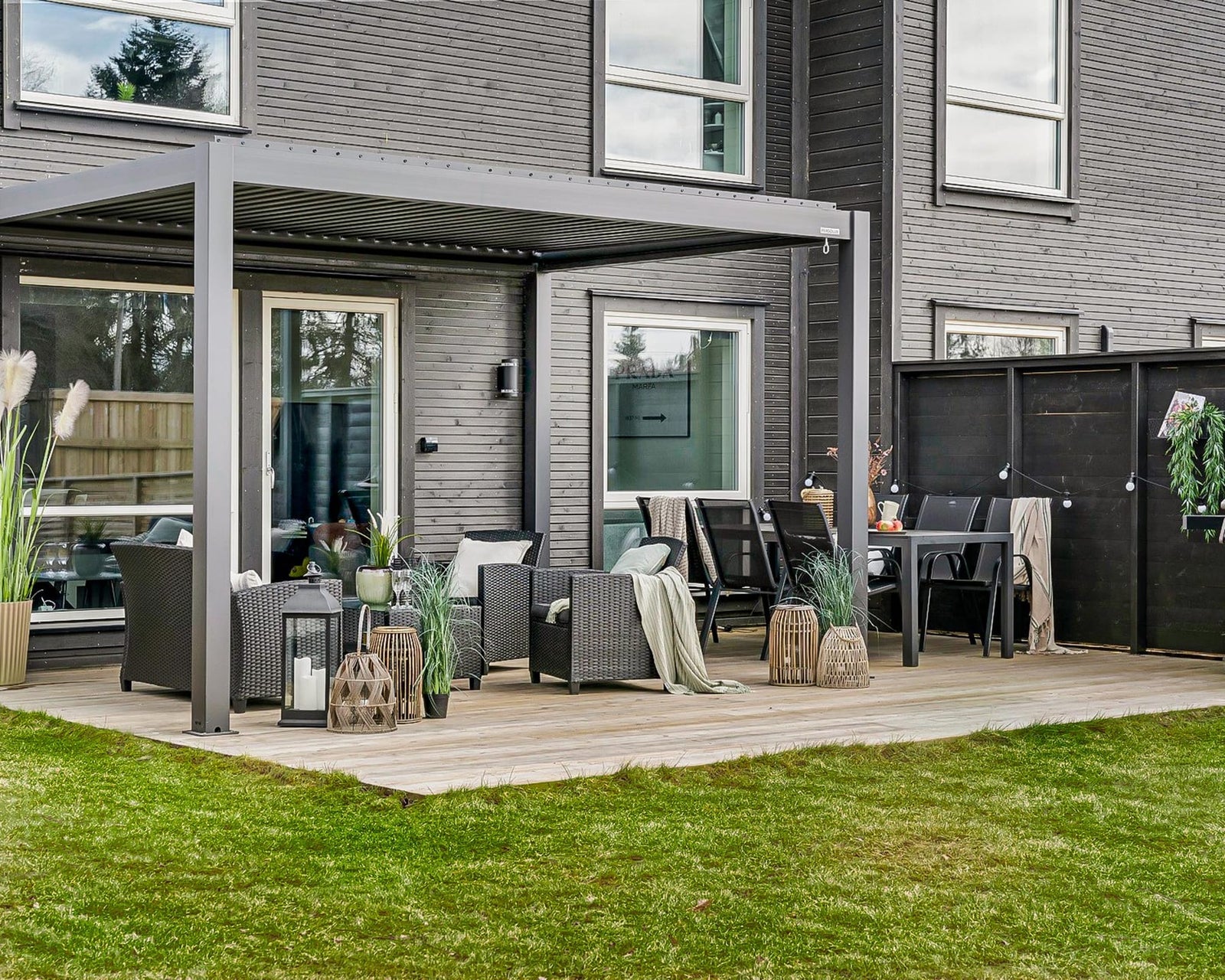 Two adults assembling an aluminium louvred pergola frame in a British back garden on a clear weekend morning